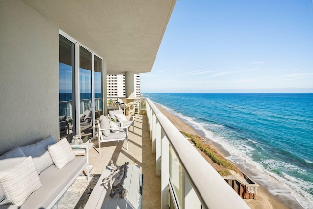 balcony featuring a view of the beach, a water view, and an outdoor living space