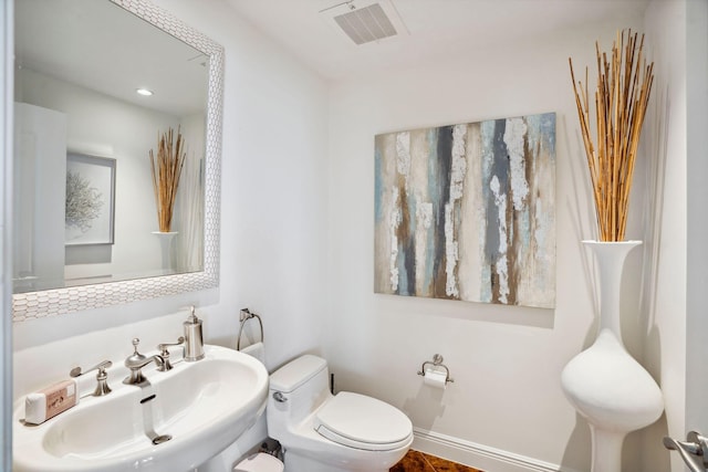 bathroom featuring toilet, baseboards, visible vents, and a sink