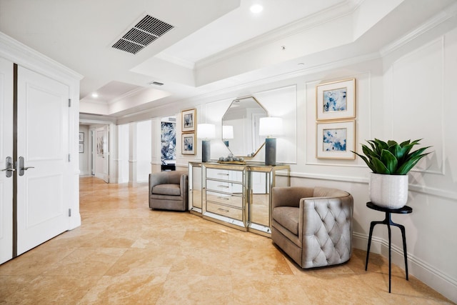 living area with recessed lighting, a decorative wall, visible vents, ornamental molding, and a raised ceiling