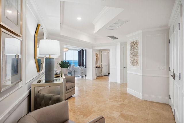 living room featuring baseboards, visible vents, a raised ceiling, and crown molding