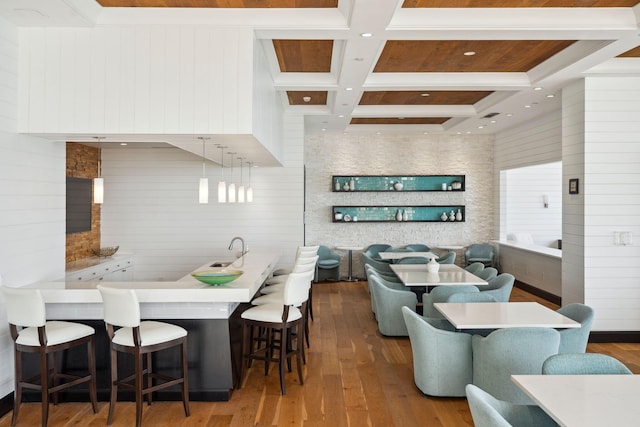 kitchen with light countertops, hanging light fixtures, coffered ceiling, and a kitchen breakfast bar