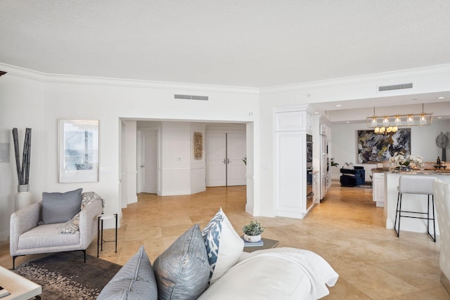 living area featuring a chandelier, ornamental molding, visible vents, and baseboards