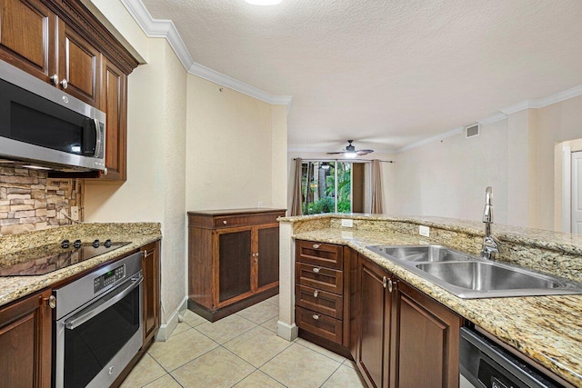 kitchen with sink, light tile patterned floors, appliances with stainless steel finishes, ornamental molding, and a textured ceiling