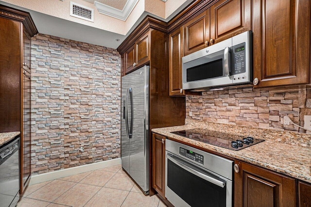 kitchen with light stone counters, light tile patterned floors, crown molding, and stainless steel appliances