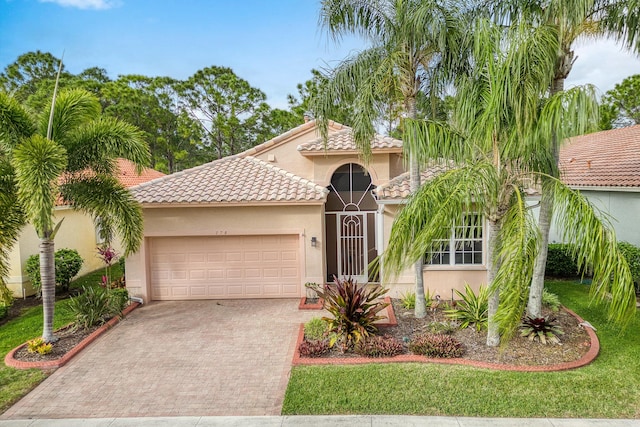 mediterranean / spanish home featuring a garage and a front lawn