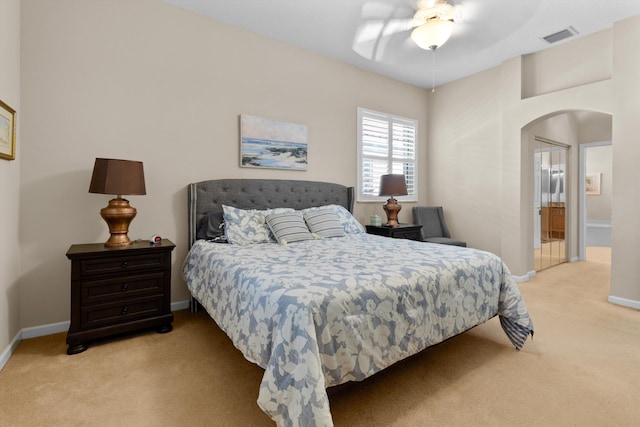 bedroom featuring light carpet, ceiling fan, and ensuite bathroom