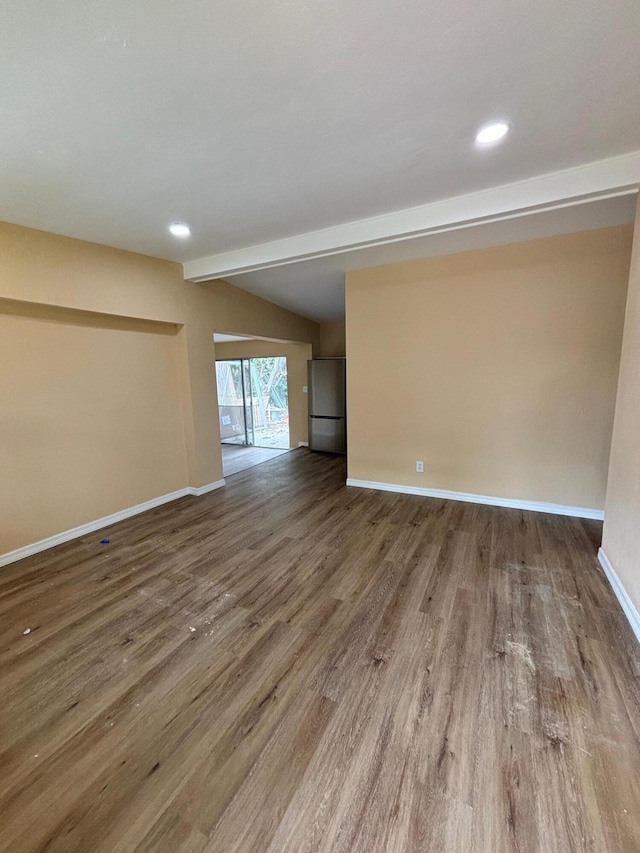 spare room featuring beamed ceiling and hardwood / wood-style floors