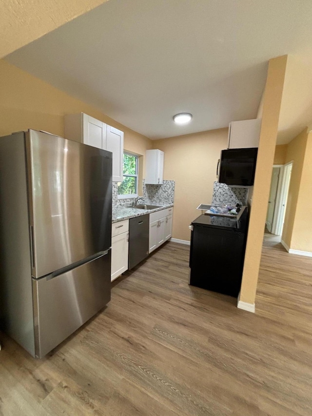 kitchen featuring sink, backsplash, stainless steel appliances, white cabinets, and light wood-type flooring