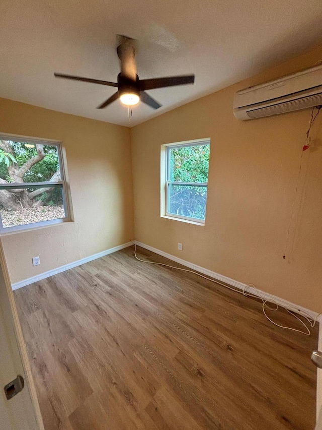 unfurnished room with ceiling fan, light hardwood / wood-style floors, and a wall mounted AC