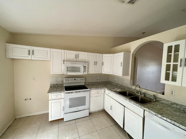 kitchen with vaulted ceiling, white cabinetry, sink, light tile patterned floors, and white appliances