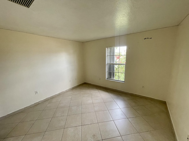 unfurnished room with light tile patterned floors and a textured ceiling