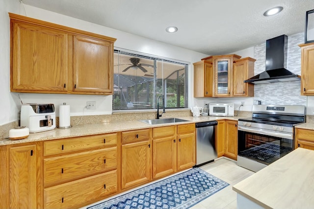 kitchen featuring stainless steel appliances, tasteful backsplash, sink, and wall chimney range hood