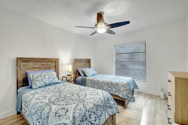 bedroom with ceiling fan, light hardwood / wood-style floors, and a textured ceiling