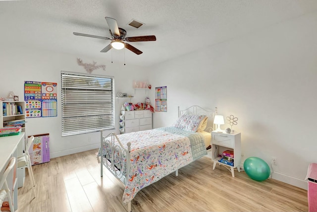 bedroom with a textured ceiling, light hardwood / wood-style floors, and ceiling fan