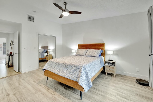 bedroom with light wood-type flooring, ceiling fan, and a closet