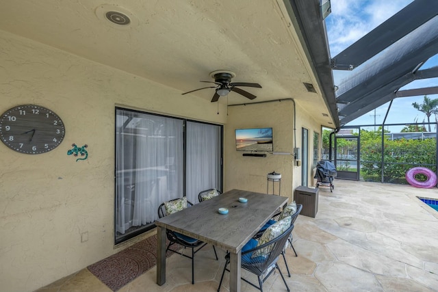 view of patio featuring area for grilling, ceiling fan, and glass enclosure