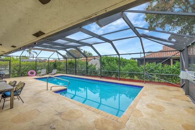 view of swimming pool with a patio area and glass enclosure