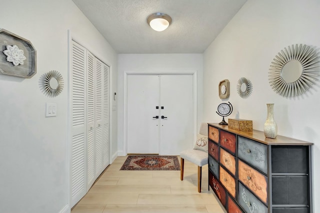 doorway to outside with light hardwood / wood-style floors and a textured ceiling