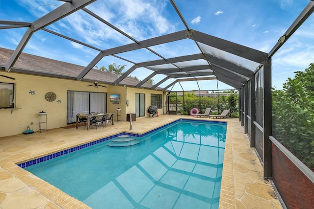 view of pool with a patio, ceiling fan, and glass enclosure