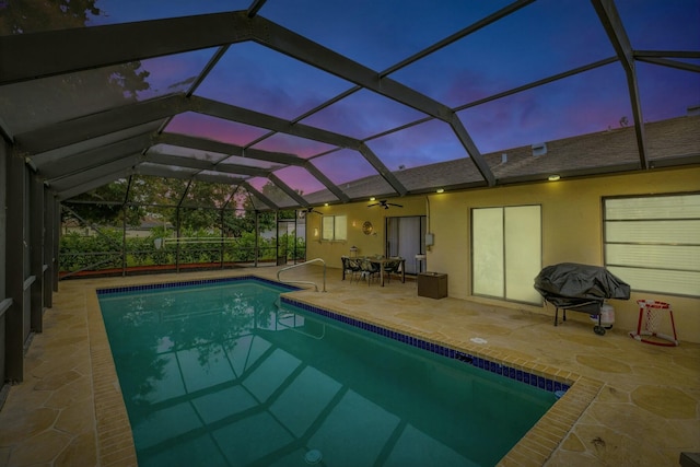 pool at dusk featuring a patio and glass enclosure