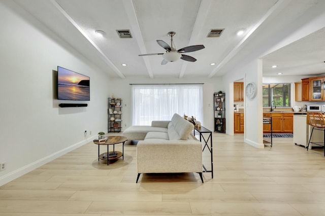 living room with beamed ceiling, sink, ceiling fan, and light wood-type flooring