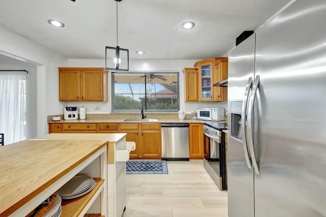 kitchen featuring appliances with stainless steel finishes, sink, pendant lighting, and ceiling fan