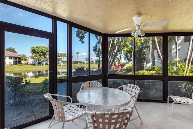 sunroom / solarium with a water view and ceiling fan