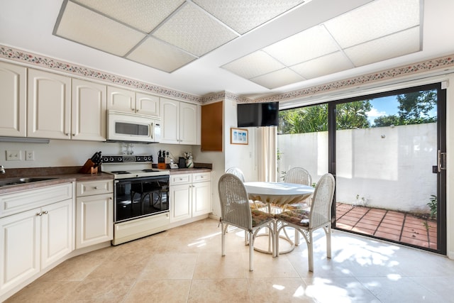 kitchen with white cabinetry, sink, light tile patterned floors, and white appliances