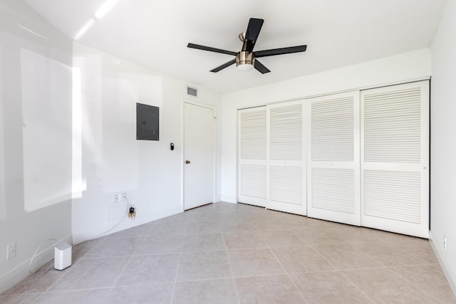 unfurnished bedroom featuring ceiling fan, electric panel, a closet, and light tile patterned floors