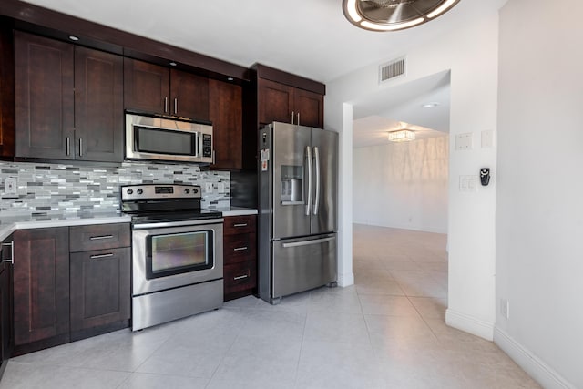 kitchen with light tile patterned flooring, appliances with stainless steel finishes, dark brown cabinetry, and decorative backsplash