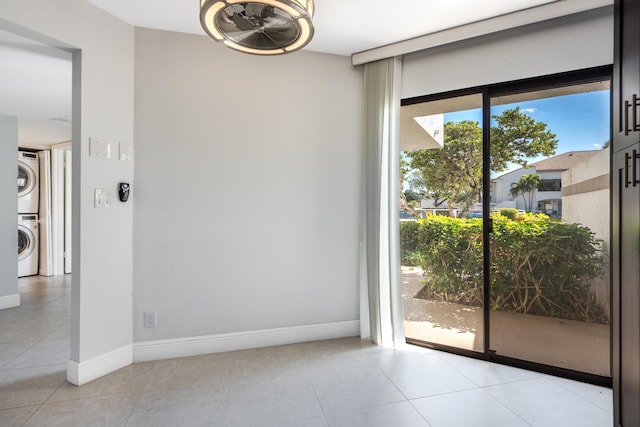 empty room with stacked washer and dryer and light tile patterned floors