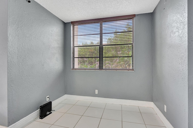 spare room featuring light tile patterned flooring and a textured ceiling