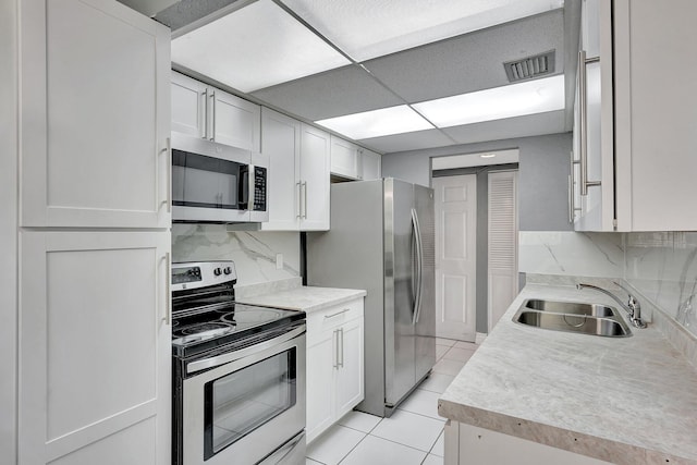 kitchen featuring sink, decorative backsplash, stainless steel appliances, and white cabinets