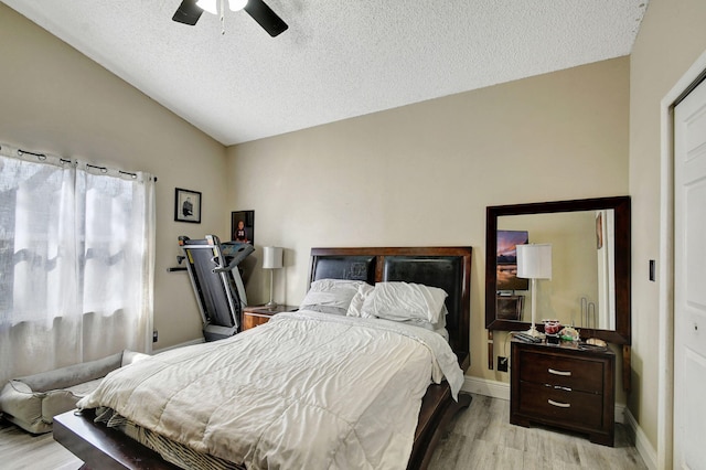 bedroom featuring baseboards, a ceiling fan, light wood-style flooring, vaulted ceiling, and a textured ceiling