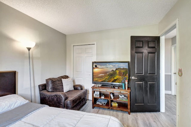 bedroom with a textured ceiling, a closet, and light wood-type flooring