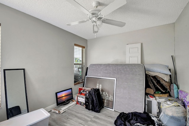 office space with a ceiling fan, light wood-type flooring, a textured ceiling, and baseboards