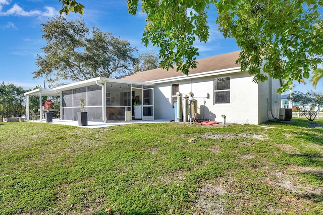 rear view of house featuring a patio, a sunroom, cooling unit, a yard, and stucco siding