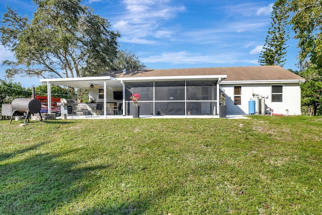 rear view of property with a sunroom, a patio area, and a lawn