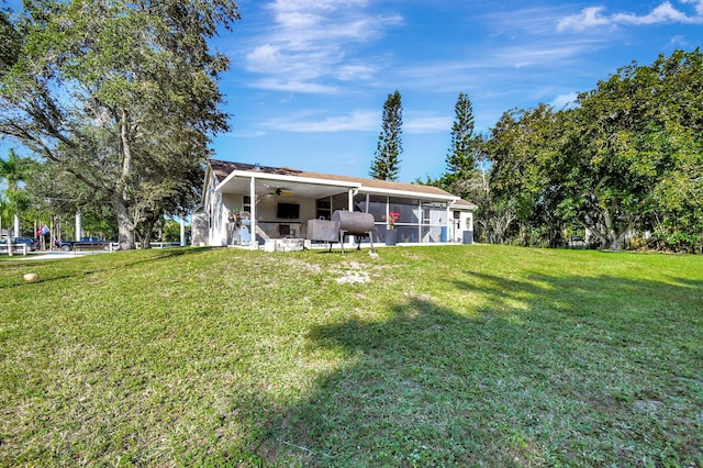 back of property with ceiling fan, a lawn, and a sunroom