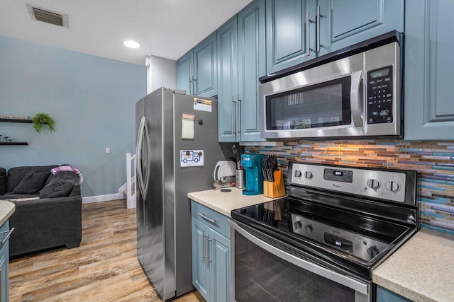 kitchen featuring blue cabinets, appliances with stainless steel finishes, and backsplash