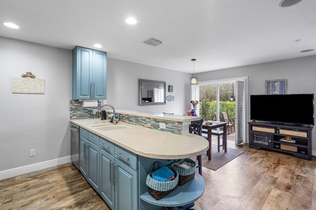 kitchen with decorative light fixtures, blue cabinets, sink, decorative backsplash, and kitchen peninsula