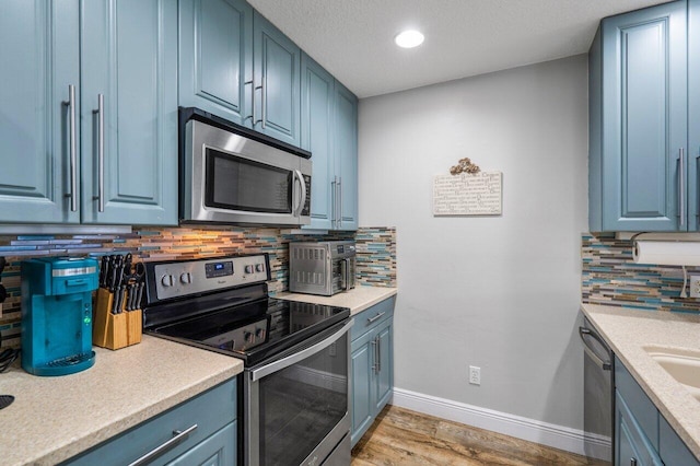 kitchen with tasteful backsplash, appliances with stainless steel finishes, and blue cabinets