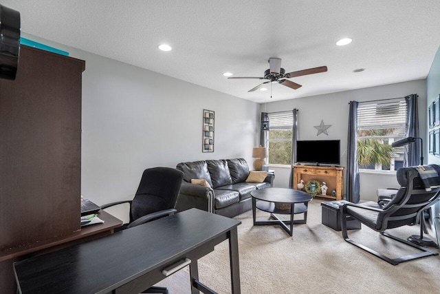 living room featuring ceiling fan, light colored carpet, and a textured ceiling