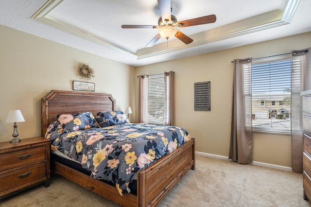 carpeted bedroom with multiple windows, a textured ceiling, ceiling fan, and a tray ceiling