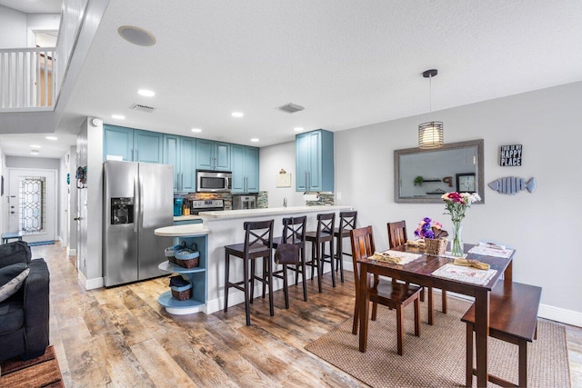 dining room featuring light hardwood / wood-style floors and a textured ceiling