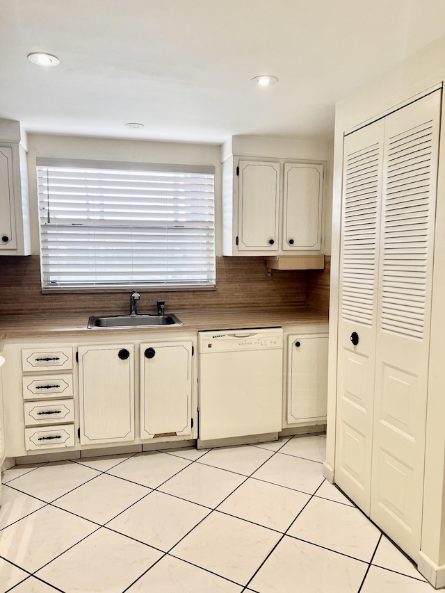 kitchen with tasteful backsplash, dishwasher, sink, and light tile patterned floors