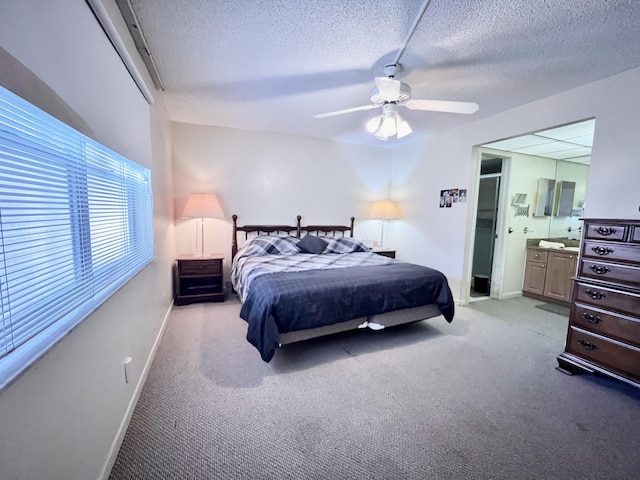 bedroom featuring a textured ceiling, light colored carpet, ceiling fan, and ensuite bathroom