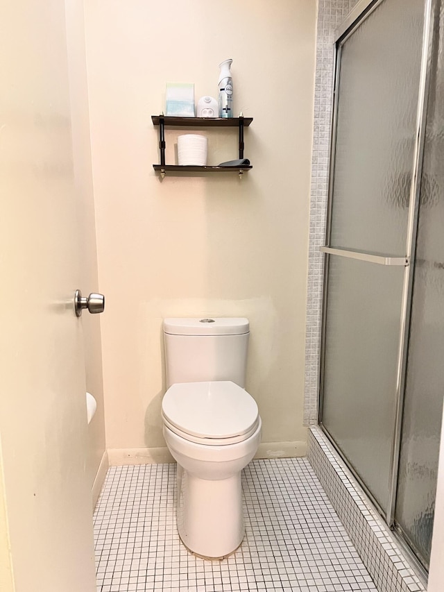 bathroom featuring toilet, tile patterned floors, and a shower with shower door