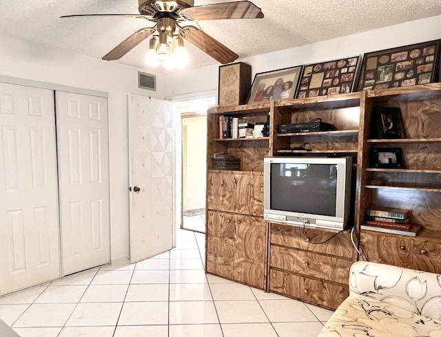 tiled living room with ceiling fan and a textured ceiling