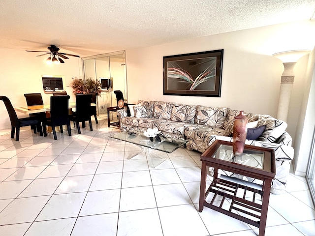 living room featuring tile patterned flooring, ceiling fan, and a textured ceiling